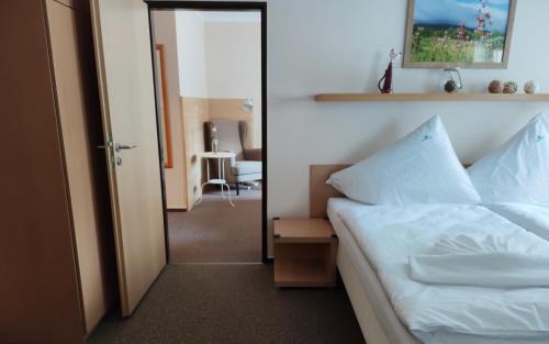 a bedroom with a white bed and a mirror at Hotel Modrásek in Kašperské Hory