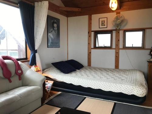 um quarto com uma cama e um sofá em ヨーコのお宿 わくわく em Toyama