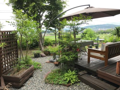 a wooden deck with a bench and an umbrella at ヨーコのお宿 わくわく in Toyama