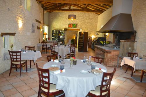 un restaurant avec des tables et des chaises blanches et une cuisine dans l'établissement Logis Domaine du Seudre, à Saint-Germain-du-Seudre