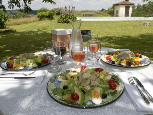a table with two plates of food and glasses of wine at Le Boisdalon in Yviers