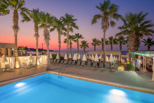 a swimming pool with palm trees and a resort at Phoenix Beach Hotel in Plános