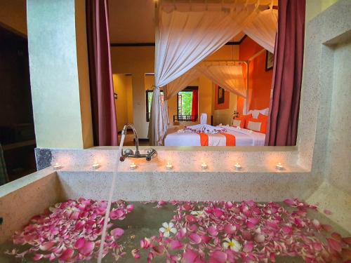 a bathroom with a tub filled with pink flowers at Residence Indochine Suite in Siem Reap