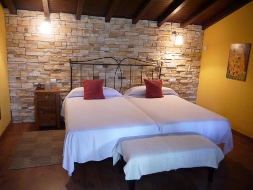 a bedroom with two beds and a stone wall at Hotel Rural Isasi in Gordexola