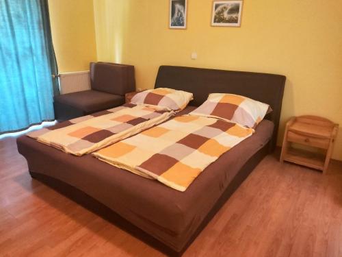 Cette chambre comprend un lit avec un canapé et une chaise. dans l'établissement Ilona Apartmanház, à Siófok