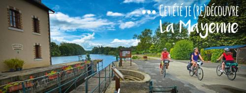 three people riding bikes on a bridge near a river at Au Pigeon Blanc in Andouillé