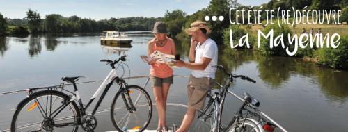 a man and woman standing on a boat with bikes at Au Pigeon Blanc in Andouillé