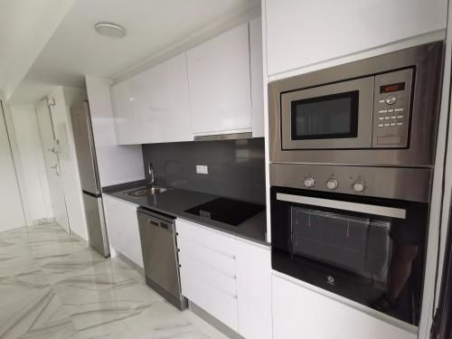 a kitchen with white cabinets and a microwave at Luxury apartment Maracuya Javea Port in Jávea