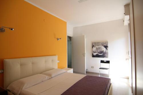 una camera con un letto bianco e una parete arancione di Appartamenti Morfeo a Pisa