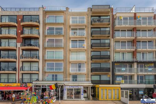 a tall apartment building with windows and people in front of it at Golvenzang 0401 in Koksijde