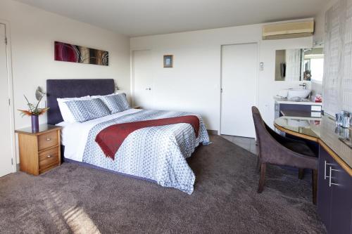 a bedroom with a bed and a desk and a sink at Allegra House in Paihia