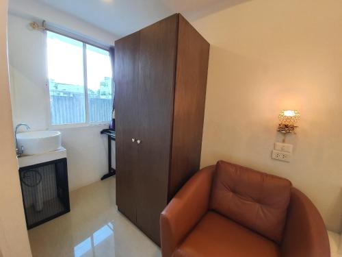 a living room with a brown couch and a cabinet at Chiang Mai Heritage House in Chiang Mai