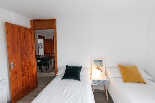 two beds in a room with a table and a door at Anayet - Plaza del Reloj en FORMIGAL - Reformado in Formigal