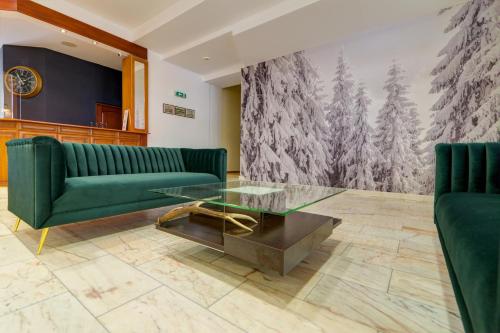 a living room with a green couch and a glass table at Apartamenty Renesans in Krynica Zdrój