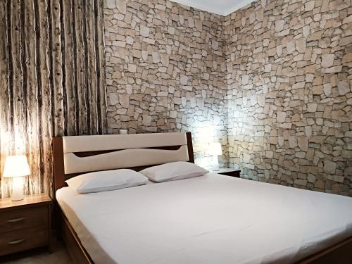 ネア・ペラモスにあるIro Apartmentの白いベッドと石の壁が備わるベッドルーム1室