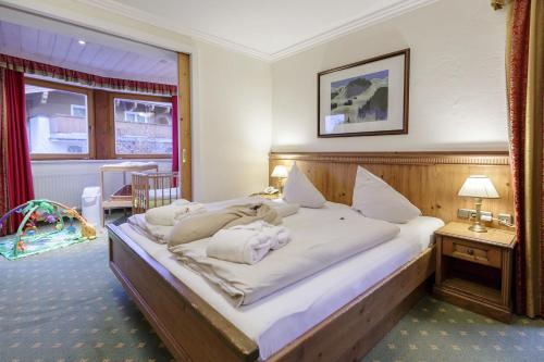a bedroom with a large bed with white sheets at Hotel Babymio in Kirchdorf in Tirol