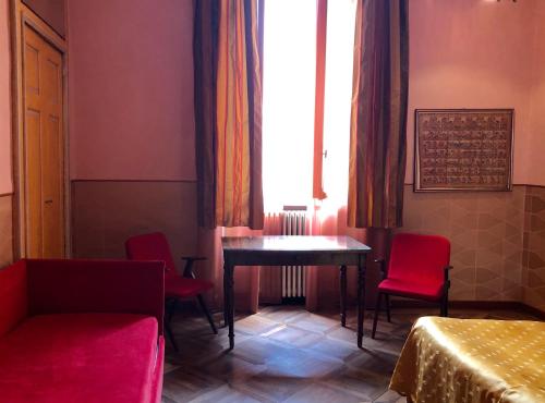 Habitación con sillas rojas, mesa y ventana en B&B Saluzzo Paesana 1718, en Turín
