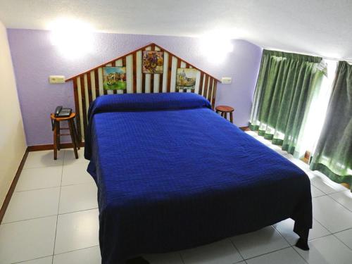 a bedroom with a bed with a blue comforter at Hotel Viar in Cabezón de la Sal