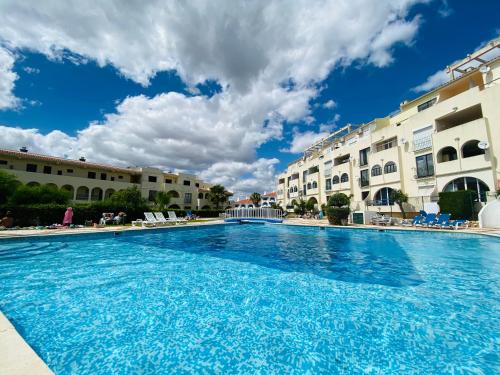 una grande piscina di fronte ad alcuni edifici di Apartamentos Poente da Aldeia ad Albufeira