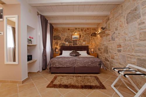 a bedroom with a bed in a stone wall at Hotel Villa Telenta in Vela Luka