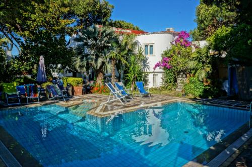 a swimming pool with chairs and a house at Villa Cinque Pini in Ischia