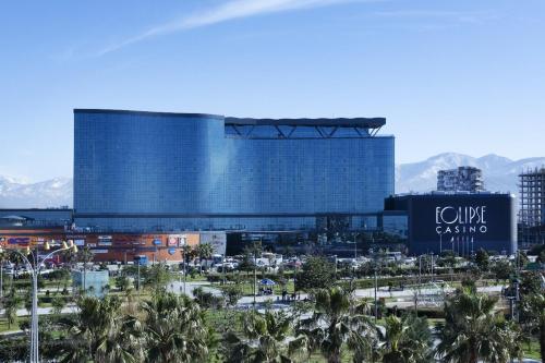 a large building with palm trees in front of it at Euphoria Batumi Convention & Casino Hotel in Batumi