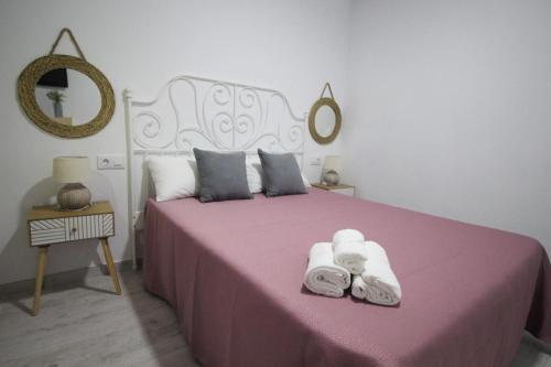 Un dormitorio con una cama rosa con toallas. en Estudio céntrico, en Conil de la Frontera