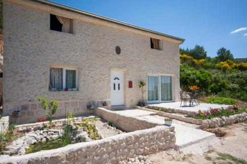 a stone house with a white door and a garden at EASY HOLIDAY in Skradin