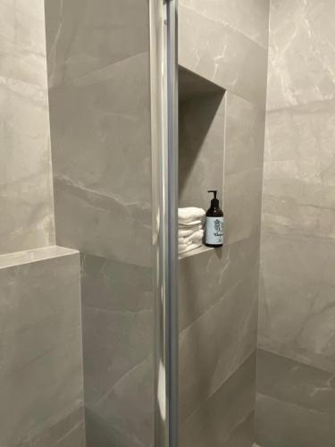 a shower stall with a bottle of soap on a shelf at Baltic Riviera Apartments - Granaria Riverside in Gdańsk