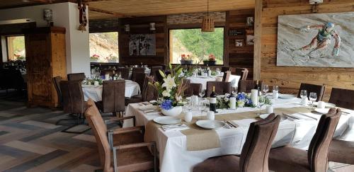 une salle à manger avec des tables et des chaises blanches dans l'établissement Chalet Marano Restaurant & Spa, à Isola 2000