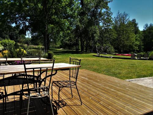 a wooden deck with a table and chairs on it at Domaine Moulin la Place in Saint-Martin-de-Saint-Maixent