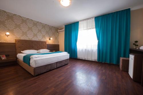 1 dormitorio con 1 cama grande y cortinas azules en Vila Levent Mangalia en Mangalia