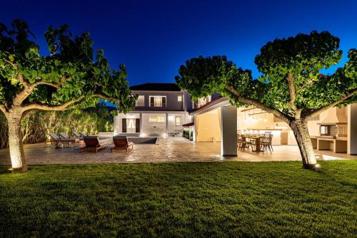 a backyard of a home at night with two trees at Aigli Villa in Zakynthos Town