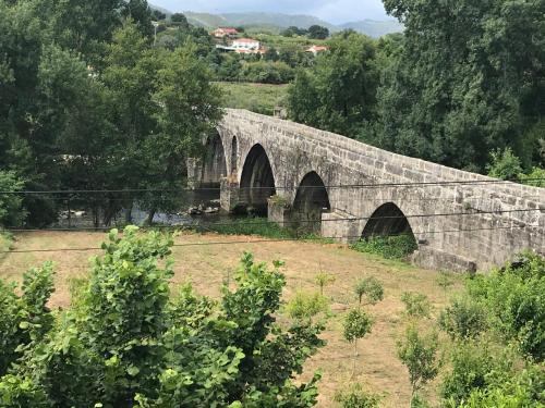 an old stone bridge with two arches on a field at Casa da Ponte do Porto in Amares