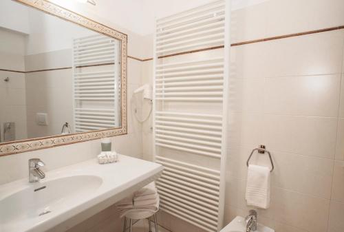 a white bathroom with a sink and a mirror at Hotel Silene Parking and Garage in Bormio