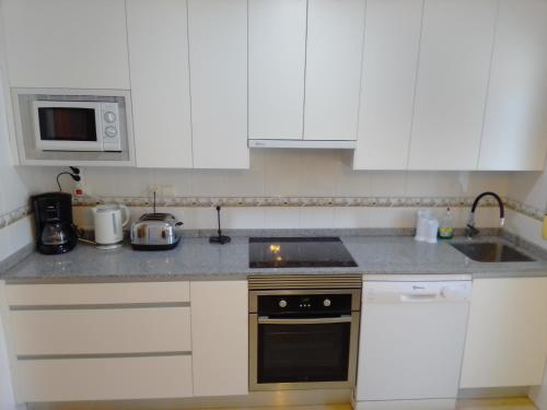 a kitchen with white cabinets and a stove top oven at Casa Luna in Santiago de la Ribera