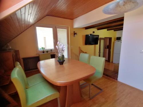 a dining room with a wooden table and green chairs at Apartma ob Savi in Čatež ob Savi
