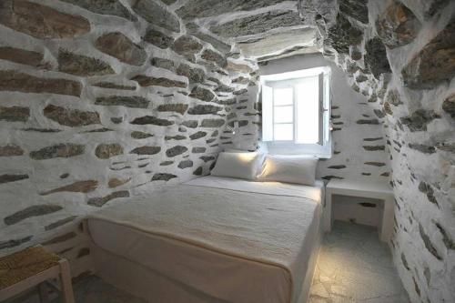 1 dormitorio con 1 cama en una pared de piedra en Tranquil cottage, en Agios Sostis