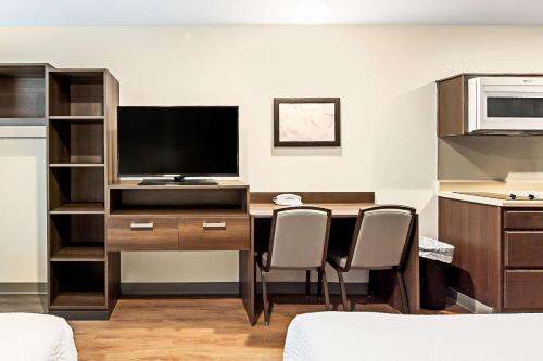 a room with a desk with a television and chairs at WoodSpring Suites Reno Sparks in Sparks