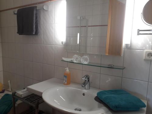 a white bathroom with a sink and a mirror at Biobauernhof Vilshof in Tannheim