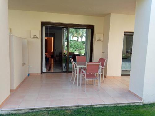 un patio con mesa y sillas en una casa en Bevs ground floor Roda Golf Apartment!, en San Javier