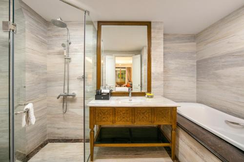 a bathroom with a sink and a tub and a shower at Hanoi Dalvostro Valentino Hotel & Spa in Hanoi