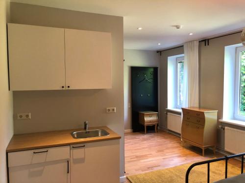 a kitchen with white cabinets and a sink at Seven Sisters Apartments with Self Check-In in Liepāja