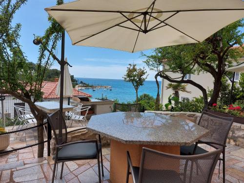 une table et des chaises avec un parasol sur une terrasse dans l'établissement SEA & HONEY, à Krk