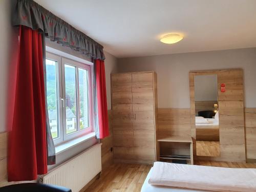 a bedroom with red curtains and a large window at Hotel Bigger Hof - Wirtshaus Platzhirsch am Jahnplatz in Olsberg