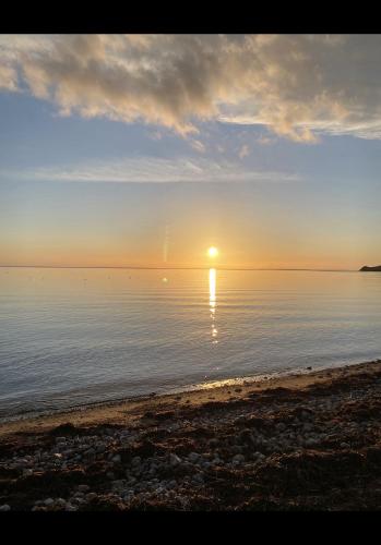 a sunset on a beach with the sun reflecting in the water at Aa Strand Camping in Ebberup