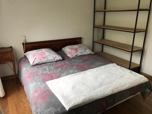 a bedroom with a bed with two pillows and a shelf at Residence Le petit paradis - La petite maison in Labastide-Rouairoux