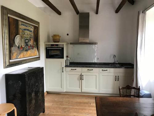 une cuisine avec des placards blancs et un tableau mural. dans l'établissement Residence Le petit paradis - La petite maison, à Labastide-Rouairoux
