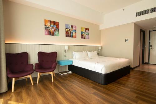 um quarto de hotel com uma cama e duas cadeiras em Higher Hotel em Bandar Seri Begawan