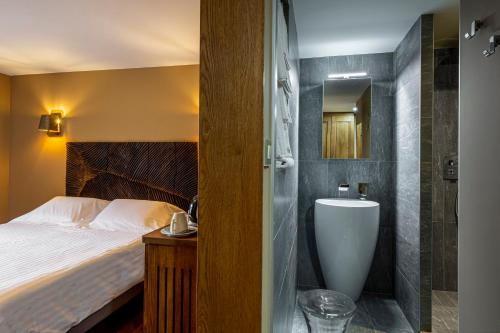 een slaapkamer met een bed en een badkamer met een wastafel bij Logis Hôtel Restaurant Auberge de la Tour in Marcolès